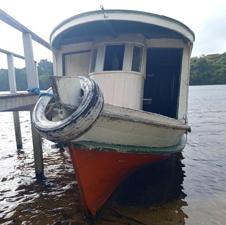 Barco de casco vermelho atracado no píer da base