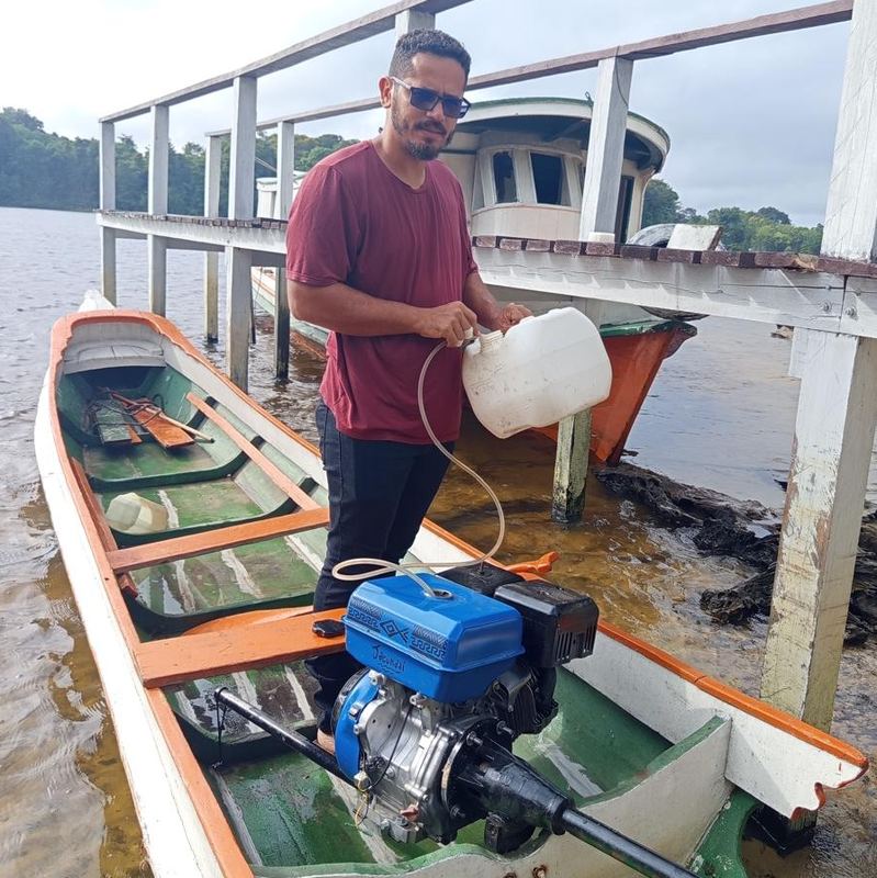 Homem trabalhando no motor da rabeta junto ao píer